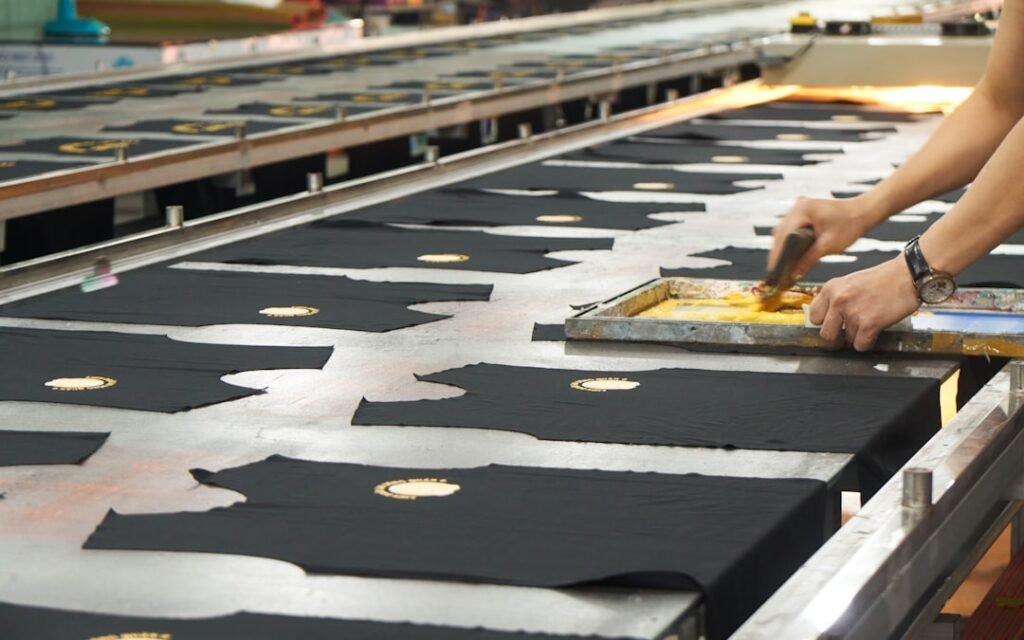 Hands screen printing fabric in an apparel workshop